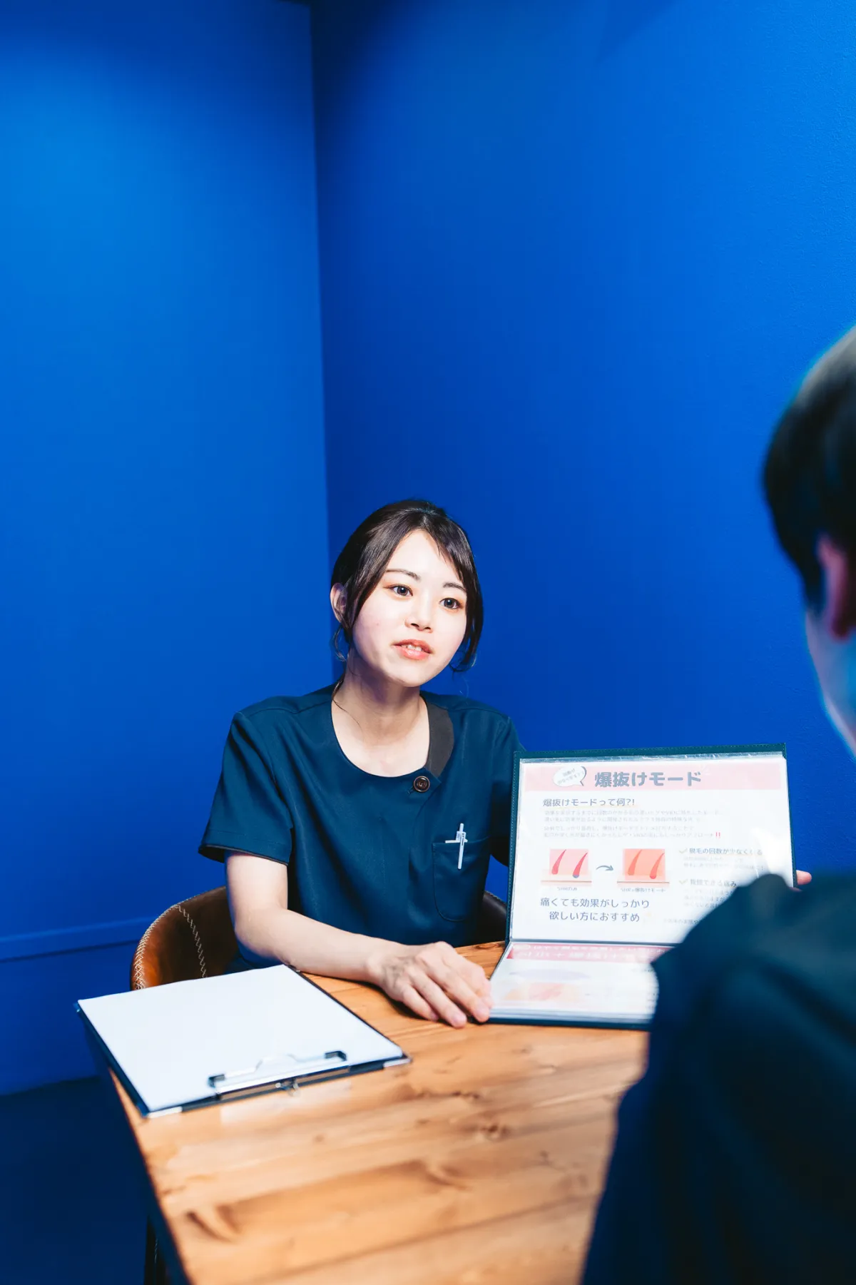 お客様に資料を示しながら説明する施術者Yuri